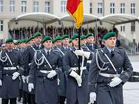 Soldaten im Dienstanzug marschieren auf einem Festplatz ein. Sie tragen eine Deutschlandflagge