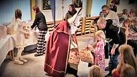 Nikolaus mit rotem Umhang und spitzzulaufenden Hut übergab Geschenke an die Kinder.