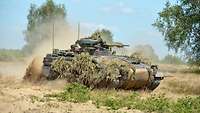 a tank drives over sandy ground