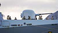 Die Besatzung eines grauen Kriegsschiffs steht auf Deck.
