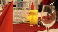 Weihnachtlich eingedeckter Tisch mit Gläsern, Servietten, Kerze und Dekoration.