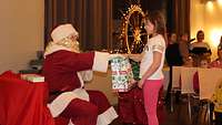 Der Weihnachtsmann überrascht ein kleines Mädchen.