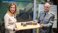 Staatssekretärin Möller und ein Soldat halten gemeinsam ein Brett mit einem Kuchen in Schlüsselform
