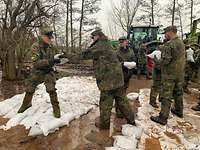 Mehrere Soldaten stapeln Sandsäcke an einem Flussausläufer.