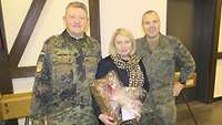 Zwei Soldaten stehen neben einer Frau, die ein Geschenk in der Hand hält. 