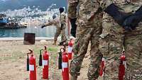 Es stehen mehrere Soldaten der Libanesen vor Feuerlöschern. Im Hintergrund sieht man zwei Soldaten an einer Feuertonne.