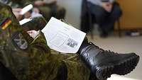 Ein Soldat sitzt und hat einen Zettel auf dem Schoss liegen