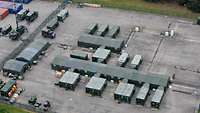 Aerial view of military tents, containers and vehicles on a concrete surface