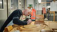 Ein Mann arbeitet an einem Modell aus Holz in einer Werkstatt