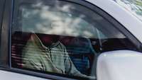 Eine Nahaufnahme von einer Person in Sturmmaske, die in einem Auto sitzt
