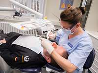 Eine Frau behandelt einen Soldaten auf dem Zahnarztstuhl