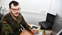 Ein Soldat sitzt am PC und arbeitet.