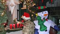 Ein Soldat mit Weihnachtsmütze zündet eine Adventskerze an