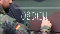 Ein Soldat schreibt mit Kreide auf einen Bundeswehr-Lkw