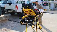 Eine rollbare Trage aus dem Krankenwagen wird von einem Soldaten geschoben. 