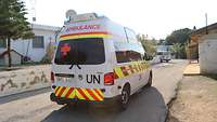 Ein Krankenwagen der UN fährt mit Blaulicht ab. 