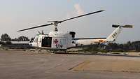 Ein weißer UN-Hubschrauber mit rotem Kreuz steht auf dem Flugfeld.