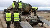 Soldaten sichern einen Schützenpanzer auf einem Schwerlasttransporter