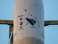 Different coats of arms and logos can be seen on the satellite carrier.