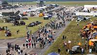 Menschen laufen auf einem Flugplatz zwischen stehenden Flugzeugen