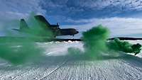 Ein Transportflugzeug landet, grün gefärbter Nebel steigt auf