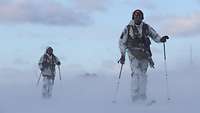 Zwei bewaffnete Kommandosoldaten laufen auf Skiern im Schneesturm
