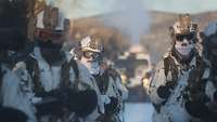 Kommandosoldaten auf Skiern werden von einem Überschneefahrzeug gezogen