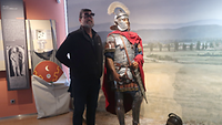 Ein Mann steht neben einer Figur, die eine Ritterrüstung trägt. 