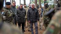 Der Bundespräsident, Verteidigungsminister und Botschafter der Ukraine stehen mit Soldaten im Wald