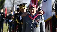 Ein US-General steht hinter einem deutschen General und legt ihm einen Orden an einem roten Band um