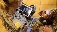 Eine Soldatin überprüft mit einem mobilen Ultraschallgerät, ob die Blutung stehen würde und „das Abbinden“ erfolgreich war.