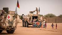 Soldaten patrouillieren mit dem Transportpanzer Fuchs in Mali. Ein Soldat spricht mit einheimischen Kindern.