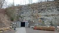 In einer Felswand ist der Eingang zur Tropfsteinhöhle.