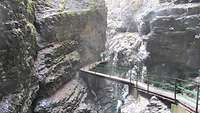 Mitten in einer Schlucht sind rechts und links nur Felsen, in der Mitte eine gesicherte Brücke über den unten reißenden Fluss.