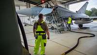 Zwei Techniker betanken ein Kampfflugzeug vom Typ Eurofighter