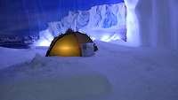 Ein Zelt wird von Innen beleuchtet und steht in einer Eiswüste. 