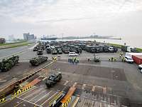 Eine große Zahl militärische Fahrzeug steht in einem Seehafen und wartet auf die Fährverladung