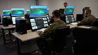 Mehrere junge Soldaten sitzen in einem Raum vor Bildschirmen mit digitalen Karten und Daten
