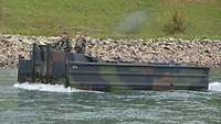 Ein Motorboot durchquert einen Fluss, darauf zwei Soldaten, die das Motorboot führen