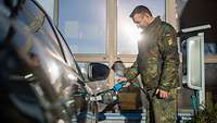 Ein Soldat lädt ein Elektrofahrzeug vom Fuhrpark der Bundeswehr