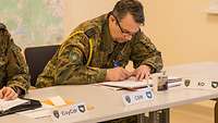 Ein Soldat sitzt an einem Tisch und macht sich Notizen