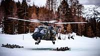 Gebirgsjäger liegen im Schnee und sichern mit ihren Waffen in alle Richtungen.