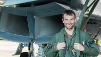 A pilot is standing under an aircraft.