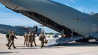 A group of soldiers walk over the rear ramp into the A400M.