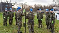 Ein Mann in Uniform sitzt an einem Tisch und registriert die wartenden Personen.