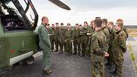 Ein Mann in Uniform sitzt an einem Tisch und registriert die wartenden Personen.