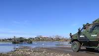 Ein militärisches Fahrzeug steht am Ufer eines Flusses.