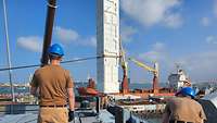 Ein weißer Container wird an Oberdeck in Position gebracht