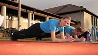 Eine junge Frau in Sportbekleidung macht einen Unterarmstütz