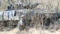 Ein Soldat kniet vor einem Schützenpanzer Puma 